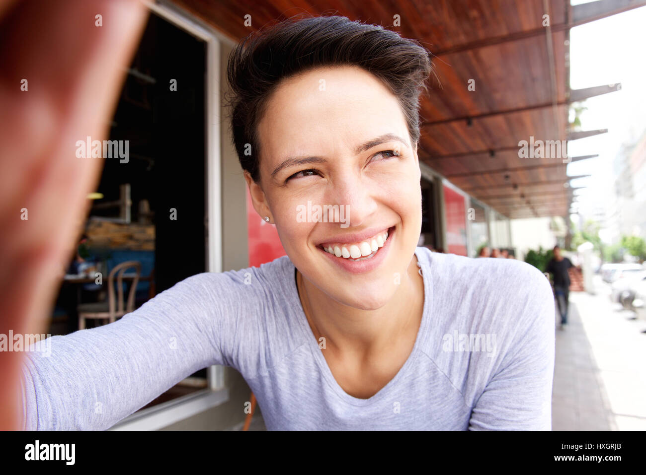 Portrait Of A Smiling Young Woman With Short Hair Taking Selfie