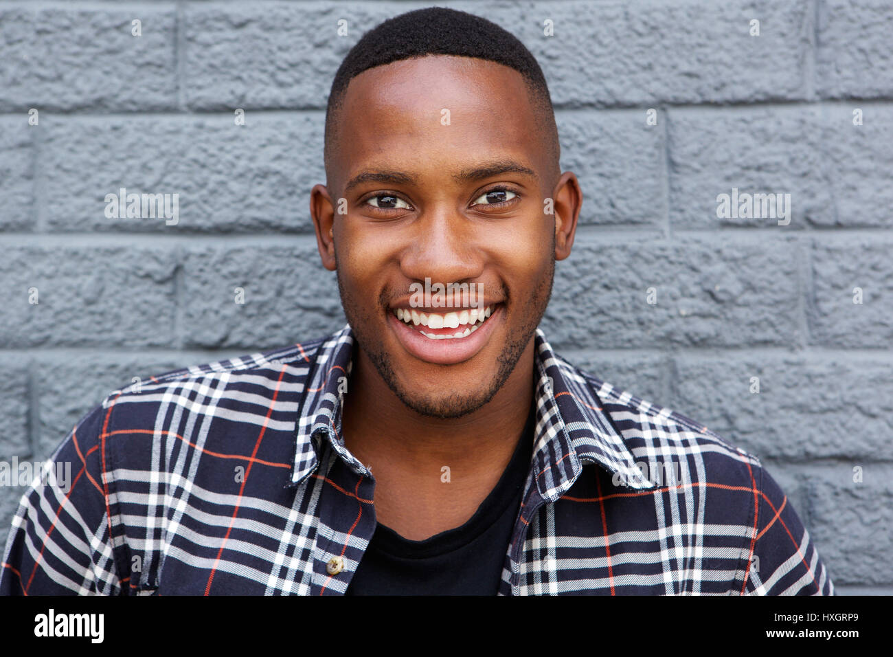Close up portrait of a cheerful young african guy smiling against gray