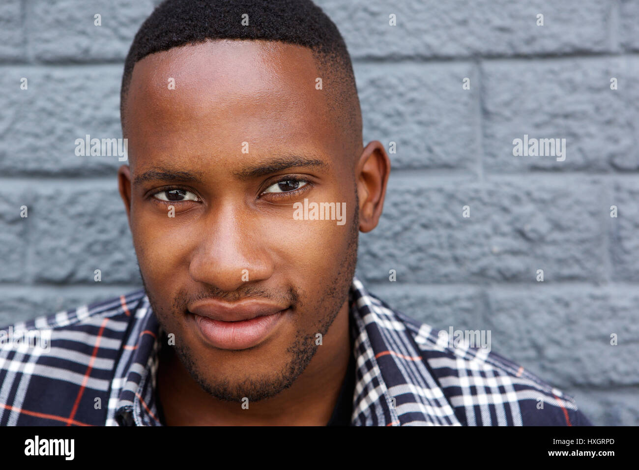 Close up portrait of a young black man against a gray wall Stock Photo ...