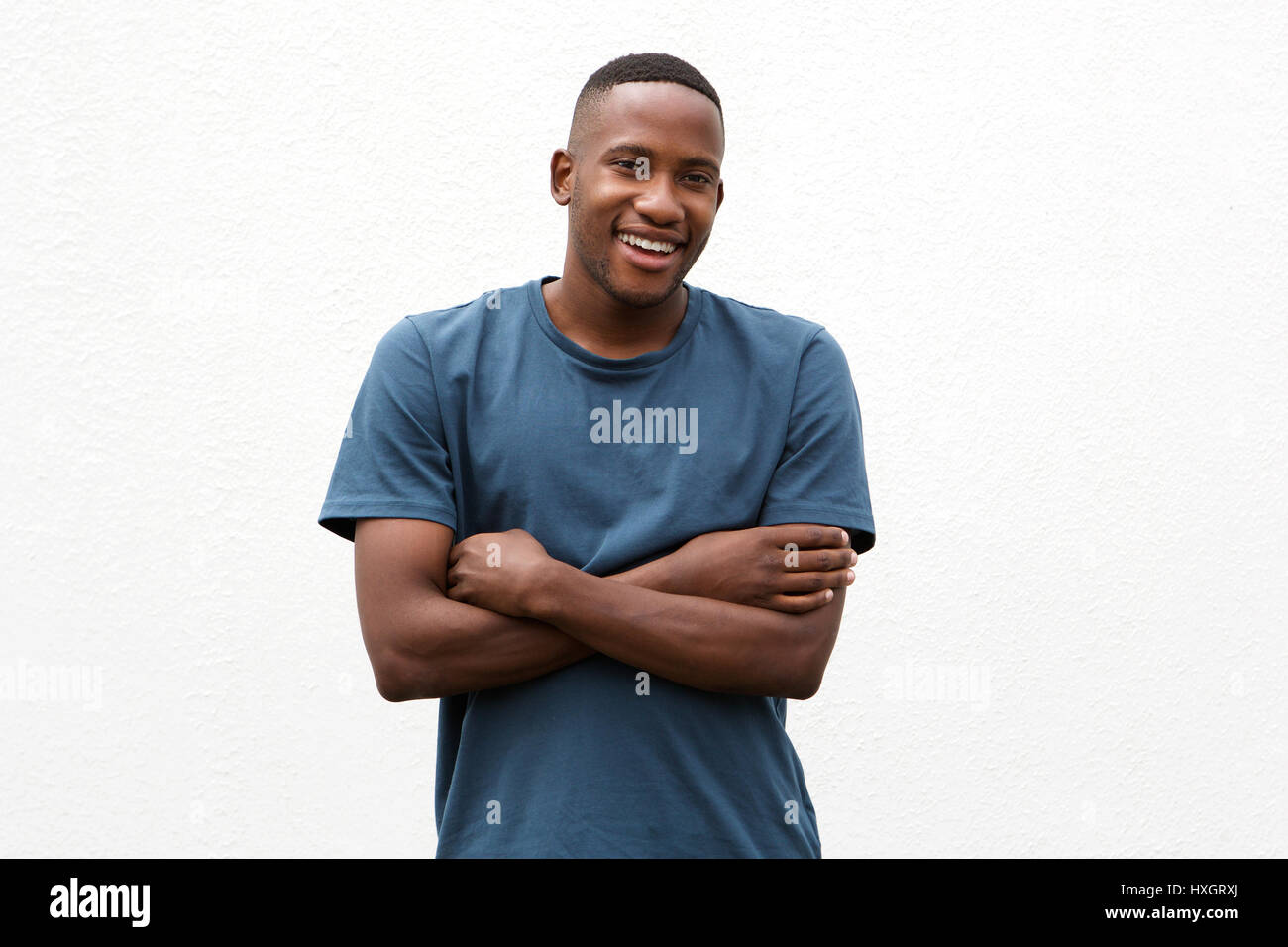 Portrait of a handsome young african man standing with arms crossed ...