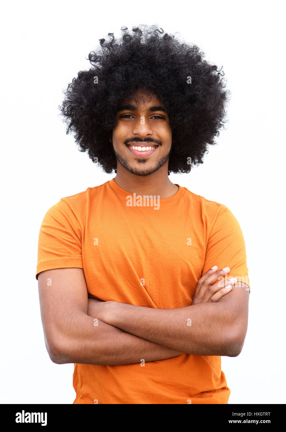 Portrait of a young black guy smiling with arms crossed against white ...