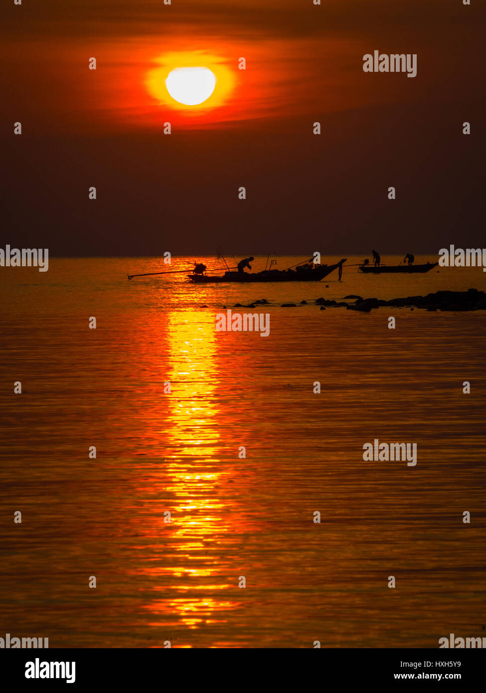 Fishermen at sunset in Thailand Stock Photo