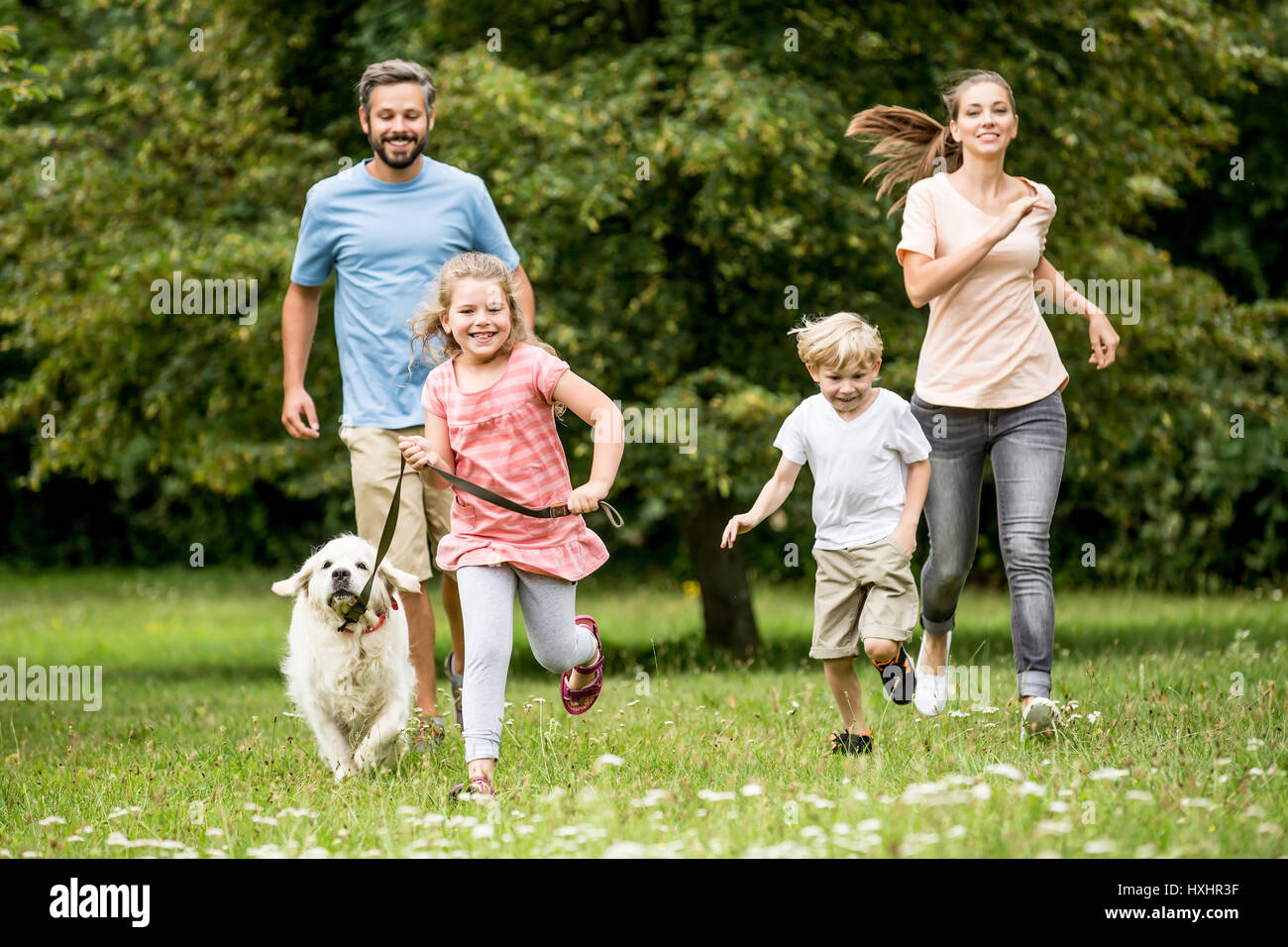 Happy children and parents with dog as family running in the nature Stock Photo