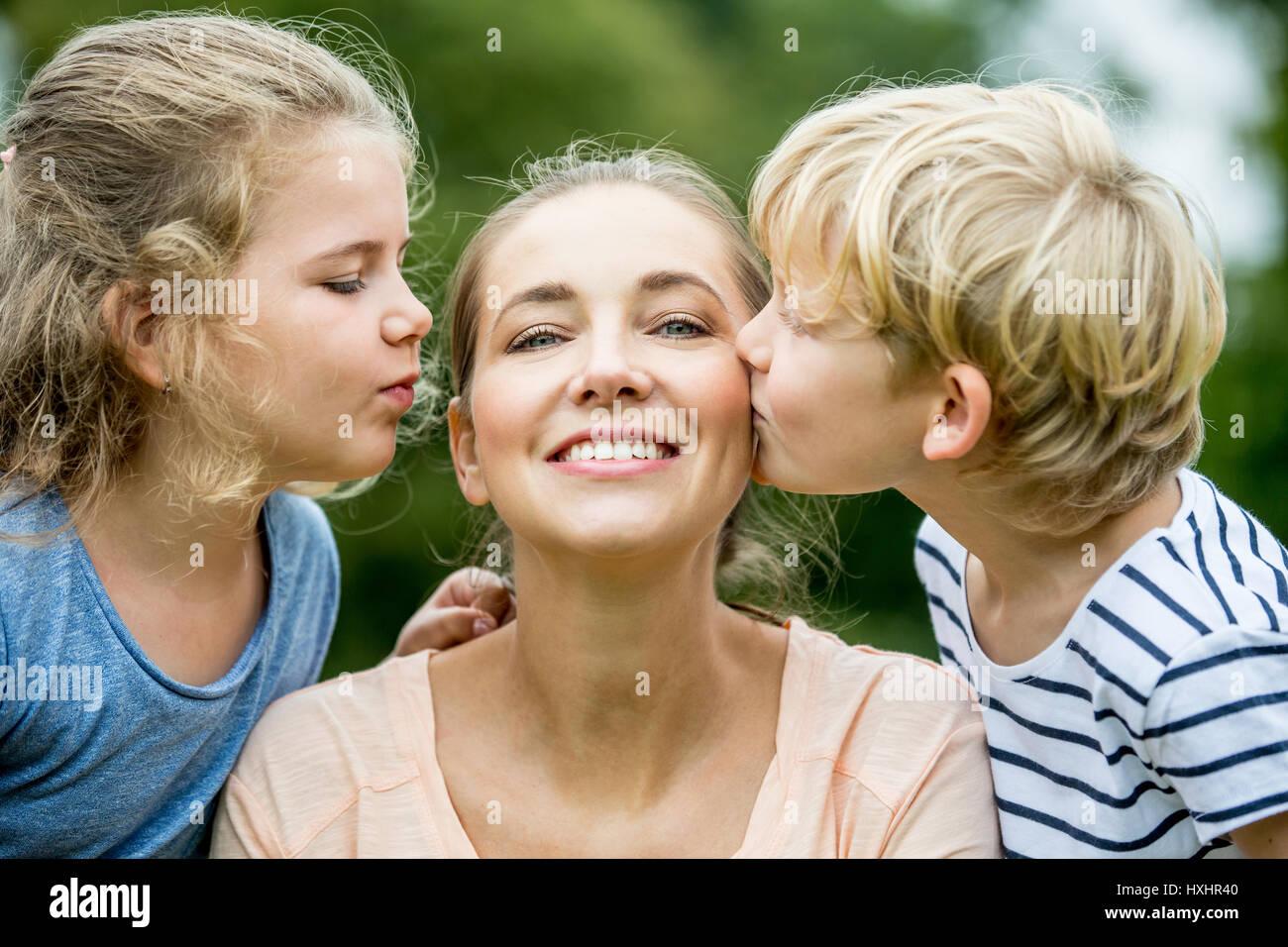 Mother and her children kissing her with love Stock Photo