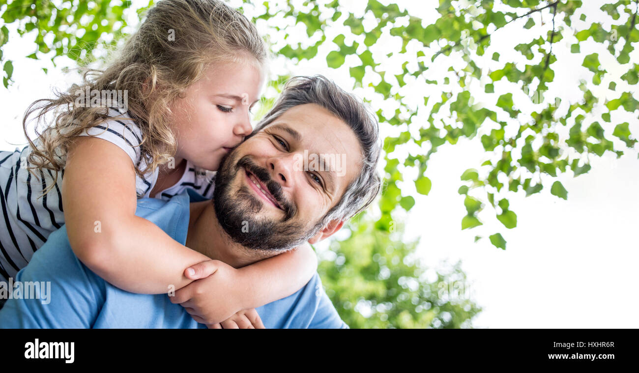 Happy daugther gives father a kiss and embrace him with love Stock Photo