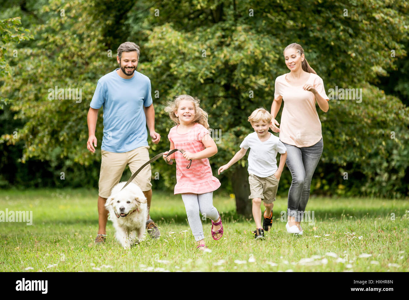 Family running with dog and having fun in summer Stock Photo