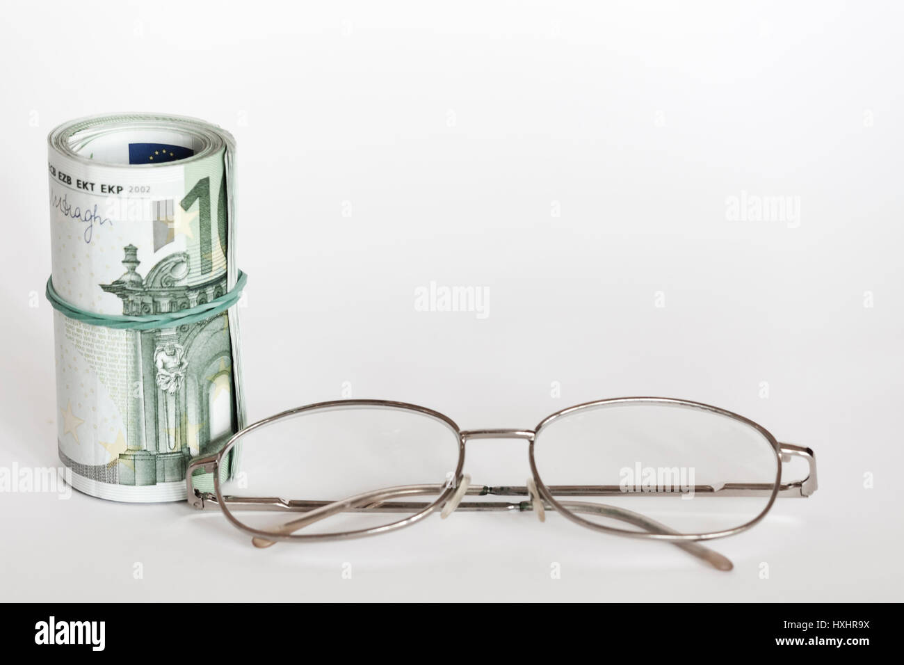 Roller of money and eye glasses Stock Photo