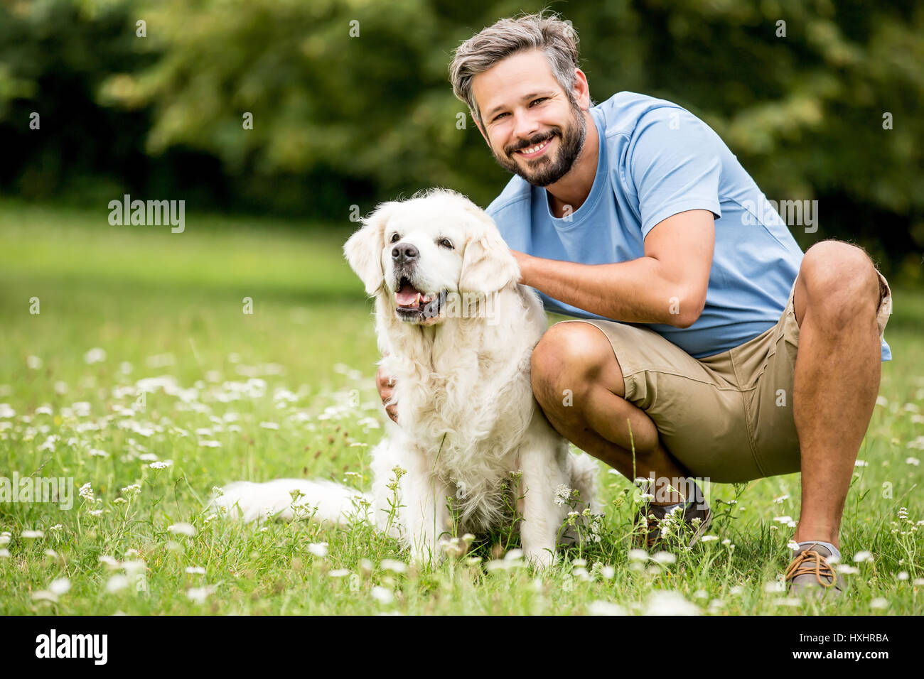 Man plays with his dog as friends together at garden in summer Stock Photo