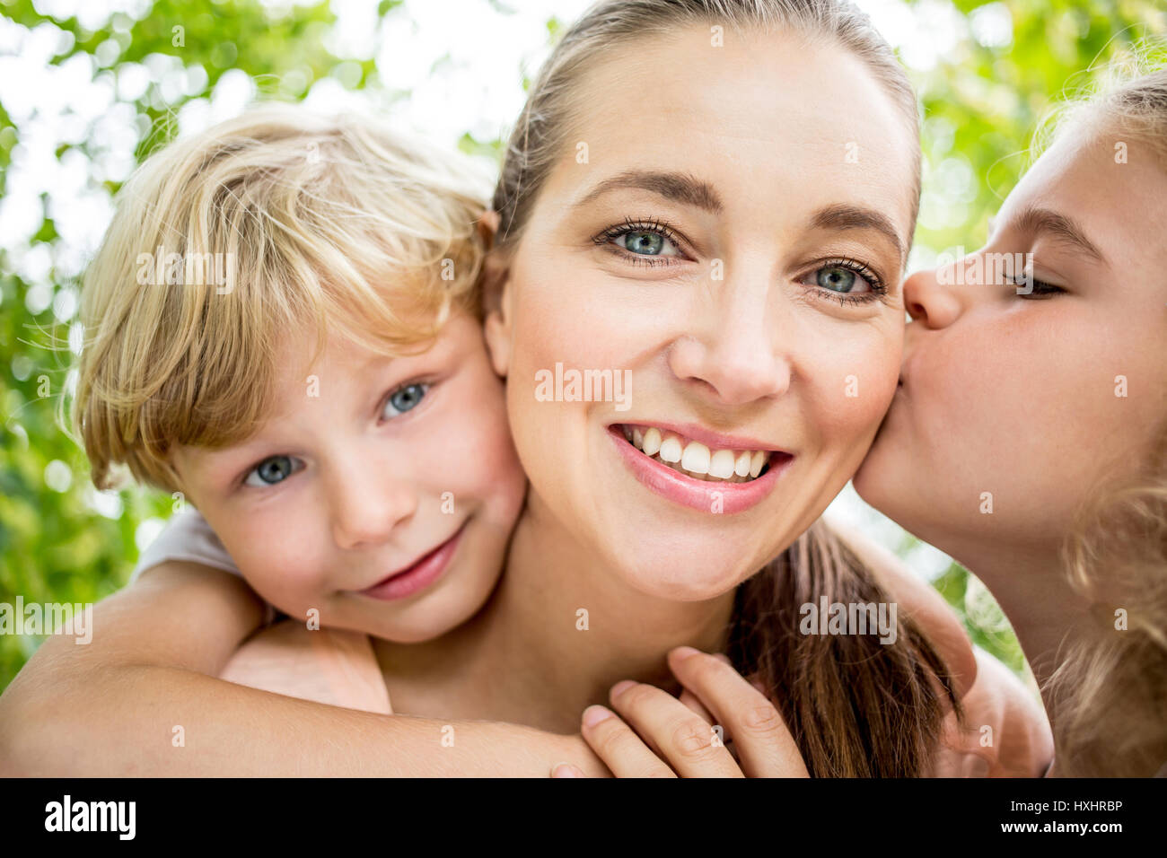 Happy mother with her children being kissed with love Stock Photo