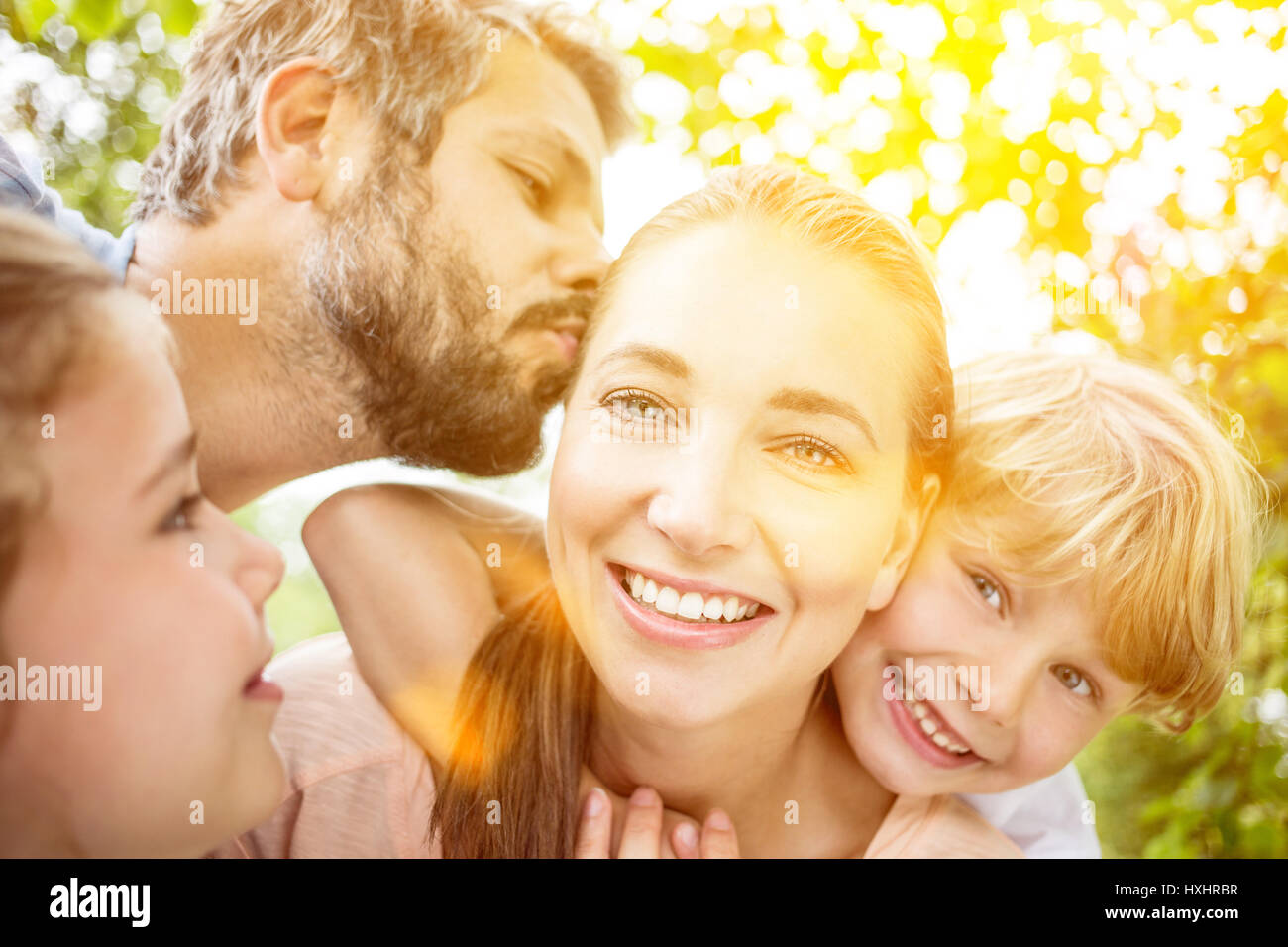 Family love with parents kissing and hugging their children Stock Photo