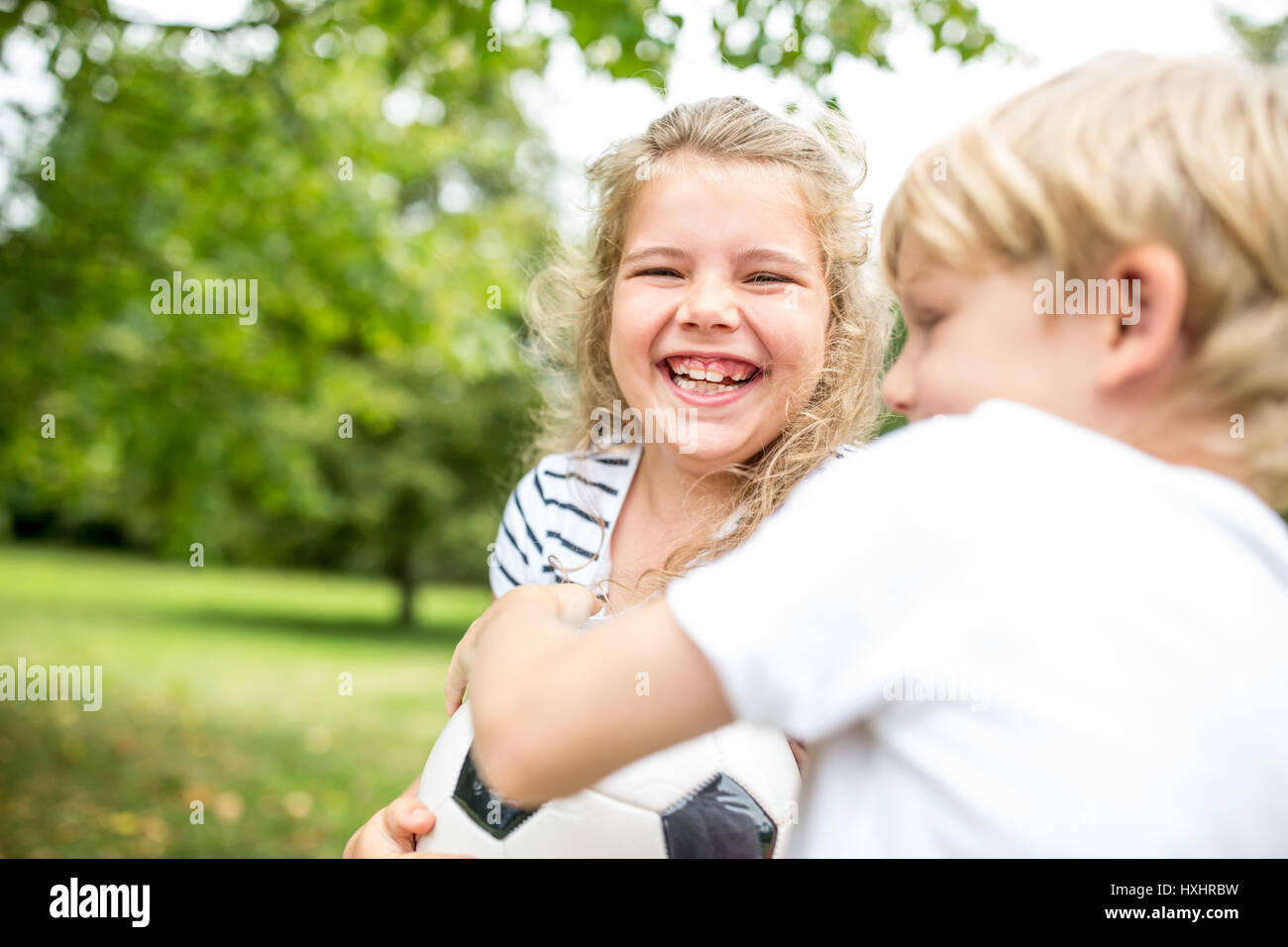 Girl laughing during controversy with brother about football Stock Photo