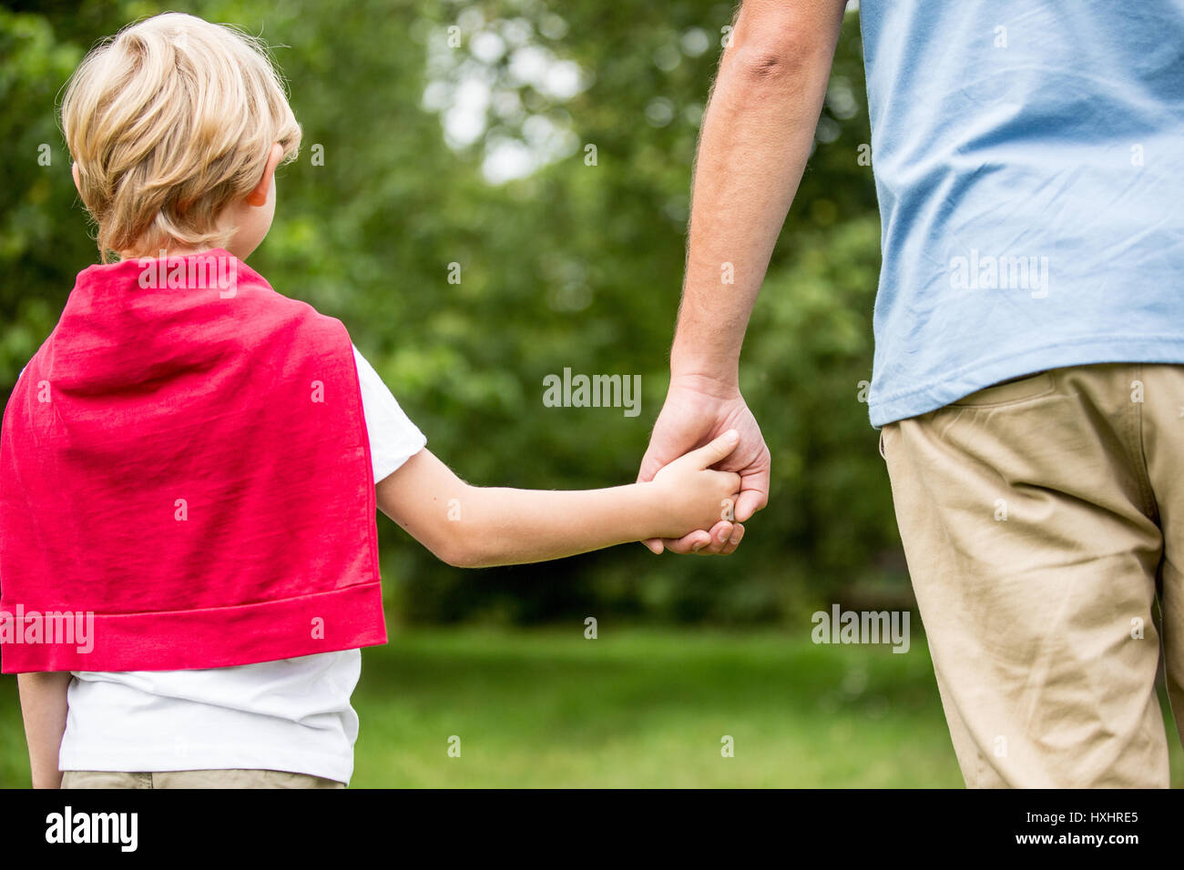 Father and son holding hands and walking as family in the nature Stock Photo