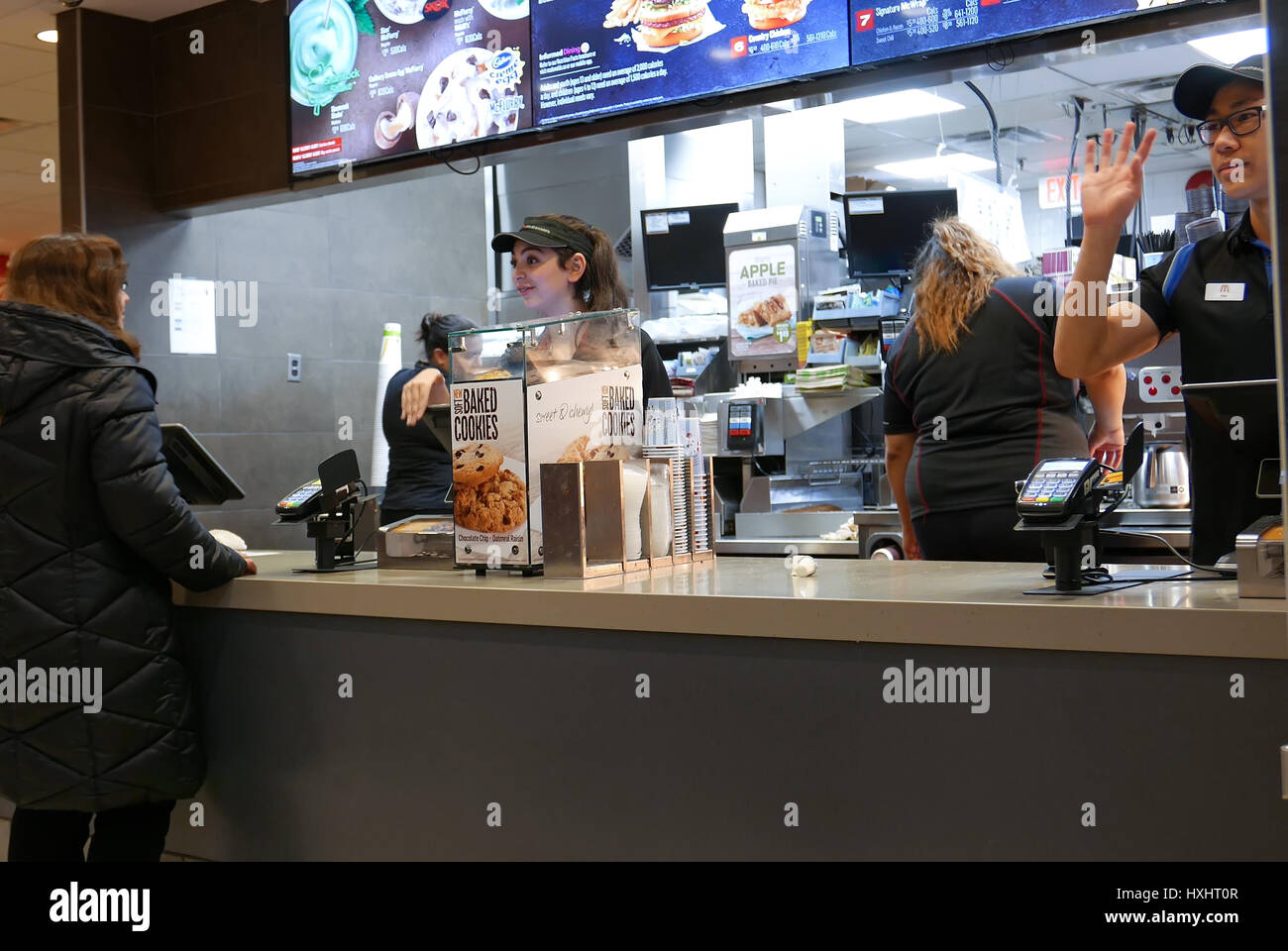 Coquitlam, BC, Canada - February 28, 2017 : Motion of worker waving for next on line customer at mcdonalds check out counter inside Coquitlam shopping Stock Photo