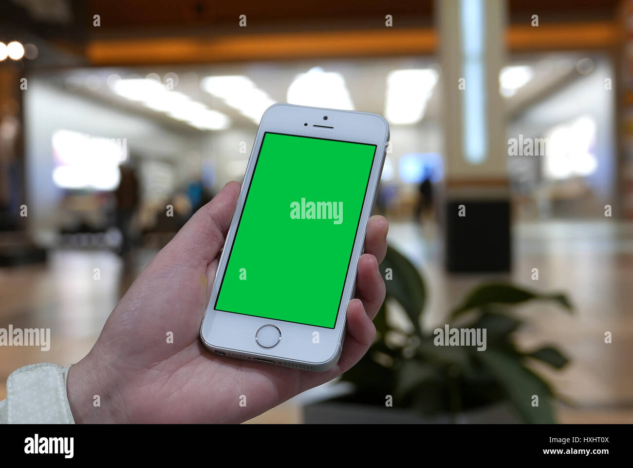 Coquitlam, BC, Canada - March 10, 2017 : Woman holds a blank smart device with a green screen for your own custom content in front of apple store Stock Photo
