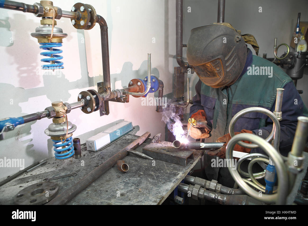 Electric Arc Welding Inside boiler room, Industrial Welder wearing protective gear, Face Shield and Gloves. Stock Photo