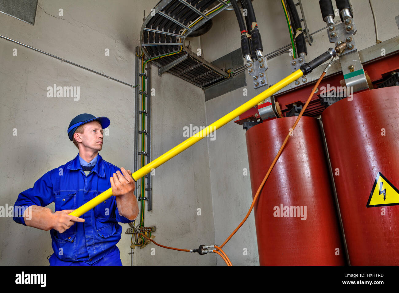 Electrical Engineer imposes temporary grounding on lowering power transformer, to ensure the safety of using an insulating rod. Stock Photo