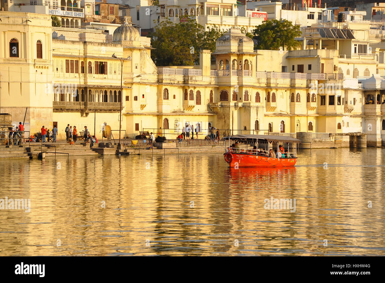 A boat takes visitors out onto Udaipur's Lake Pichola, view City Palace as a backdrop Stock Photo