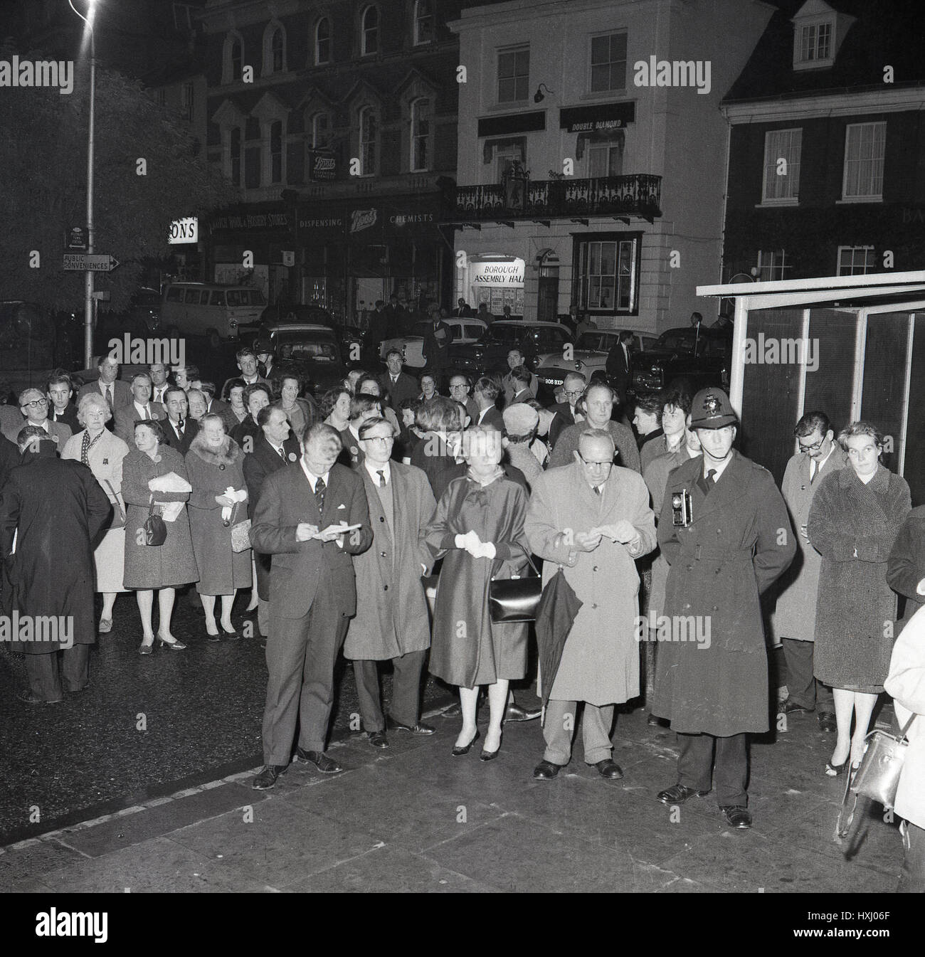 1960s, historical, evening time and people wait in high street, Aylesbury for the result of constituency vote in the British General election, England. Stock Photo