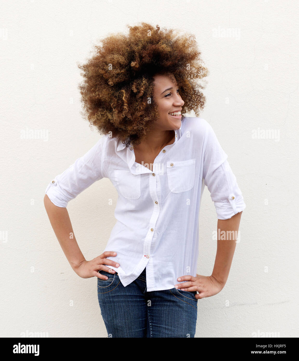 Portrait of a smiling young woman standing against white background ...