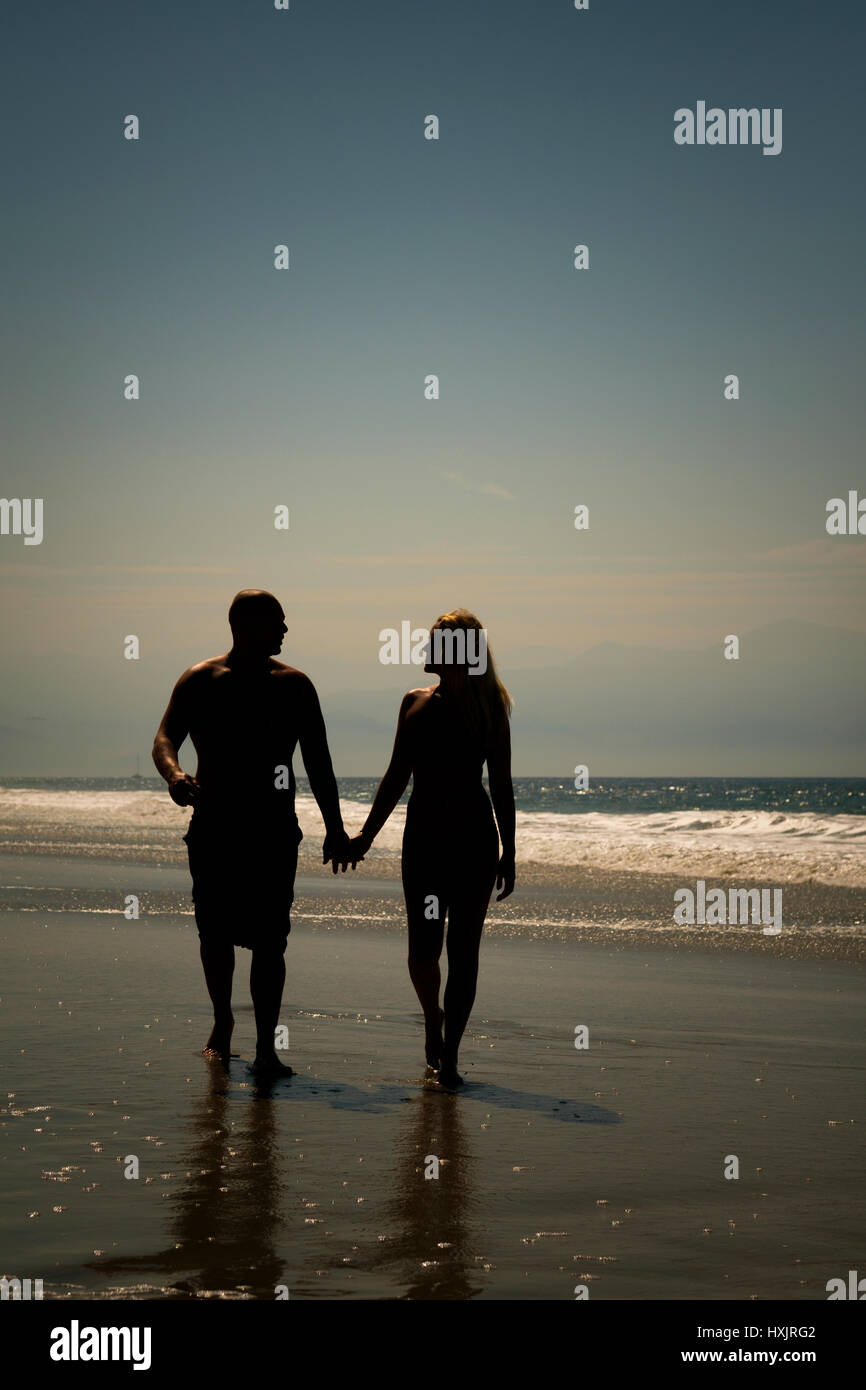 Silhouette Of A Couple Holding Hands On Beach At Sunset Stock Photos ...