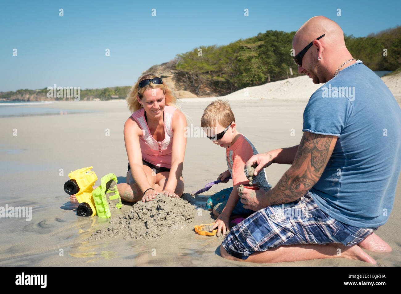 Family of 3 playing in the sand on the beach, Father, mother, toddler son. Riviera Nayarit, Mexico Stock Photo