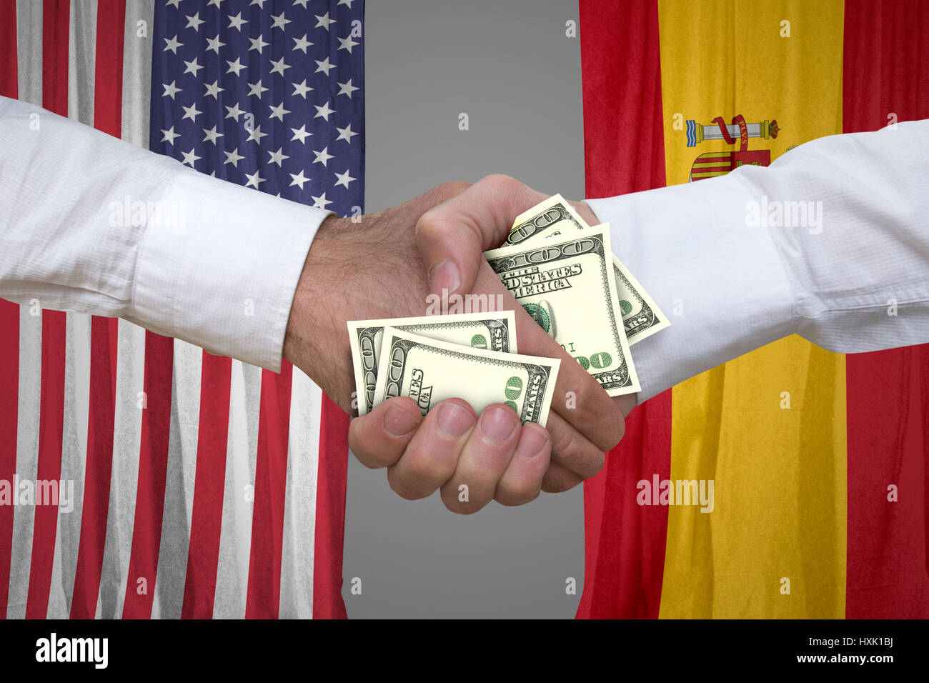 100 dollar bills handshake with USA and Spanish flags background. Stock Photo