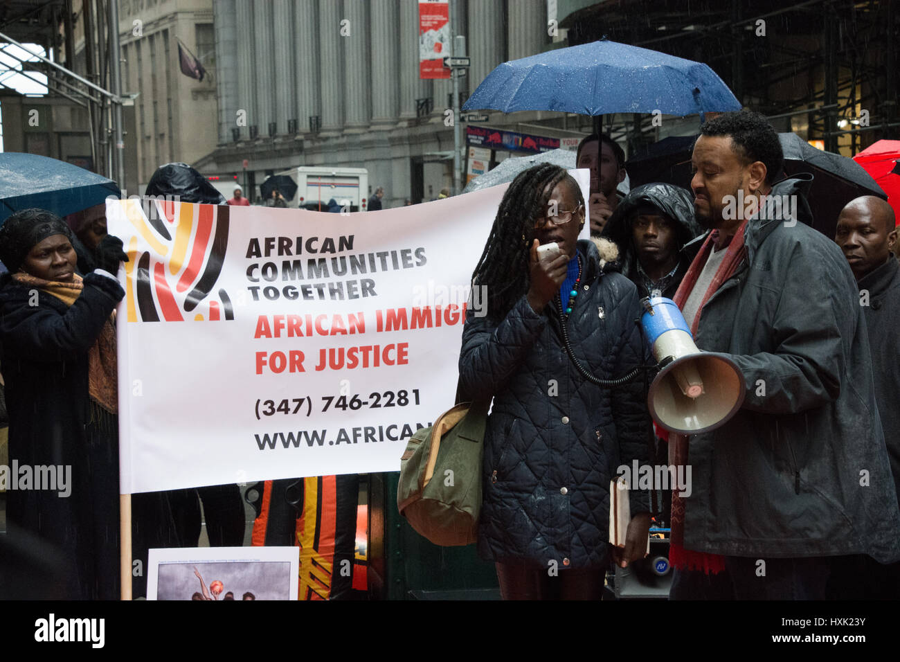 New York City, USA. 28th Mar, 2017. Elizabeth Ajok, a refugee, speaks for refugee rights at Wall Street rally as Amaha Kassa, director of African Communities Together, looks on. A coalition of social justice groups led by African Communities Together rallied in front of the Trump Building on Wall Street then marched to the courtyard of Trinity Church to begin a 24-hour camp-in to protest Trump administration refugee policies. More than one-third of refugees in the U.S. are reportedly Africans. Credit: M. Stan Reaves/Pacific Press/Alamy Live News Stock Photo