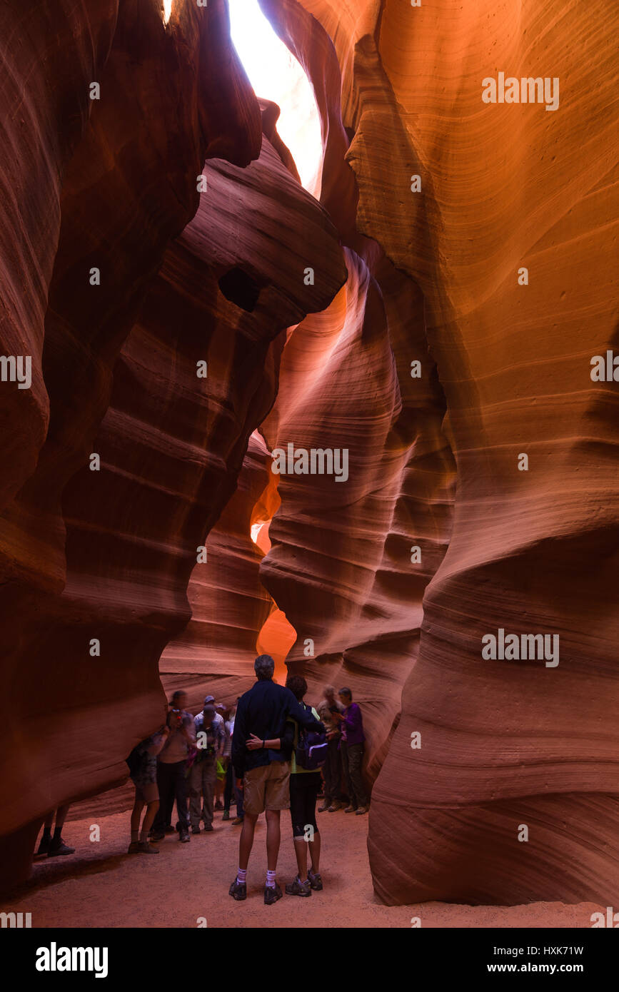 Tourists walking and looking at a section of the sandstone eroded slot canyon in Upper Antelope Canyon, Arizona Stock Photo