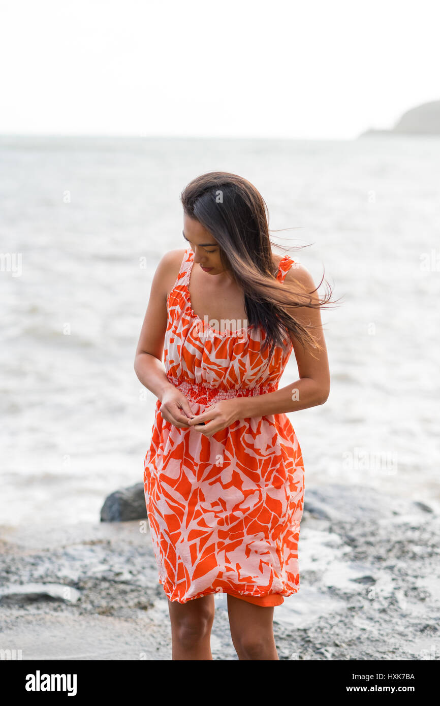 Lifestyle portrait of an attractive Hawaiian woman wearing a flower dress at Kahana Bay on Oahu Hawaii. Stock Photo
