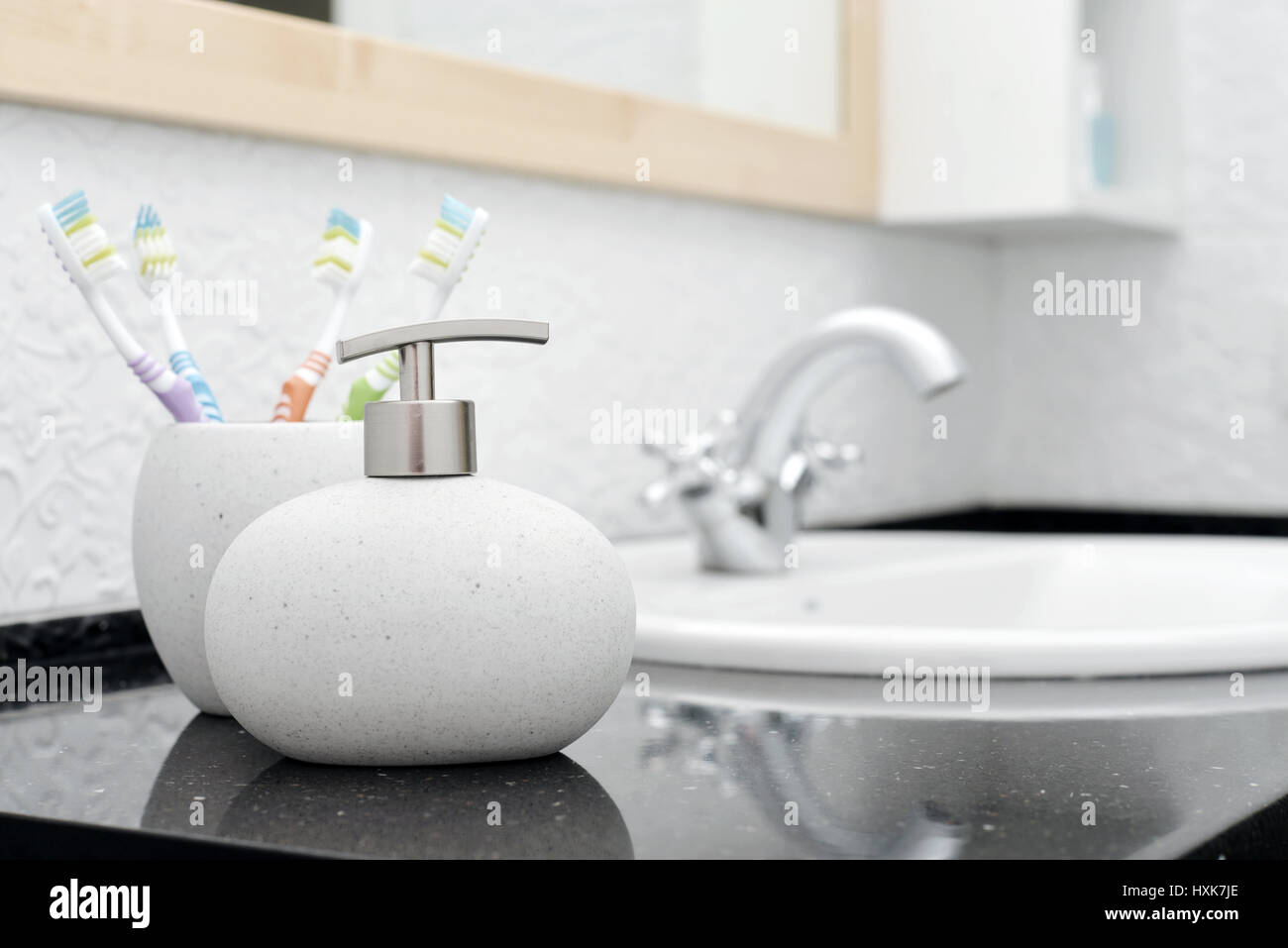 Bathroom sink and faucet with toothbrushes and soap dispenser Stock Photo -  Alamy