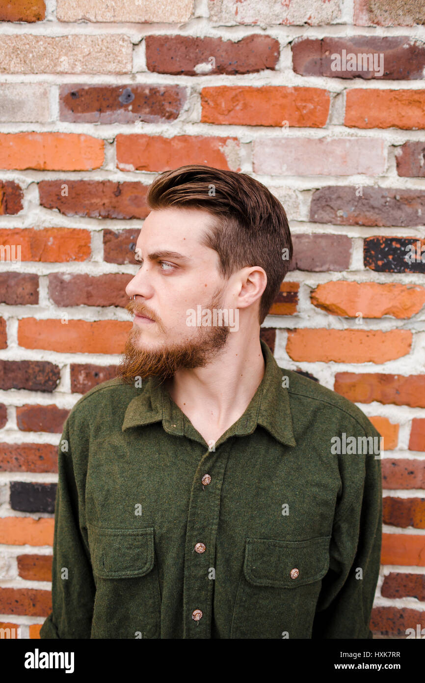Hipster posing outdoors for the camera with a fashion forward style and a modern man appearance. Stock Photo
