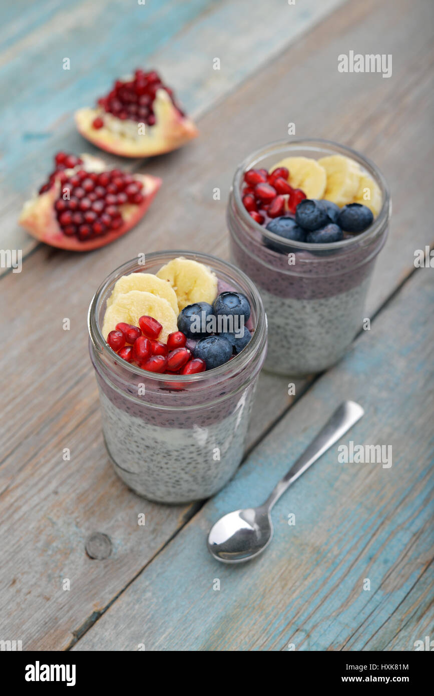 Pudding with chia seeds, yogurt and fresh fruits in glass jars on wooden background Stock Photo