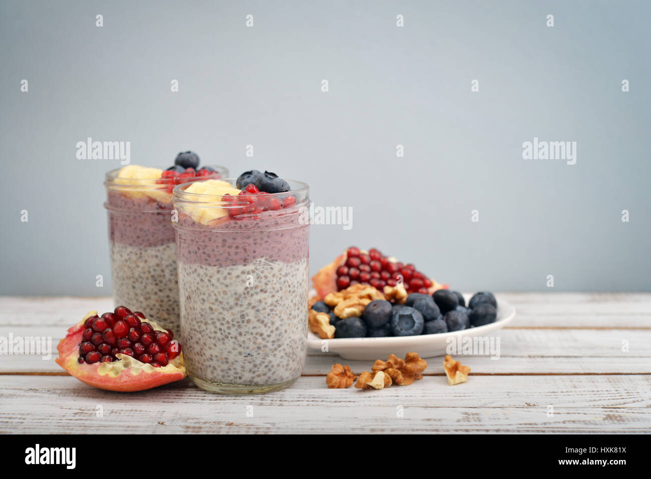 Pudding with chia seeds, yogurt and fresh fruits in glass jars on light background Stock Photo