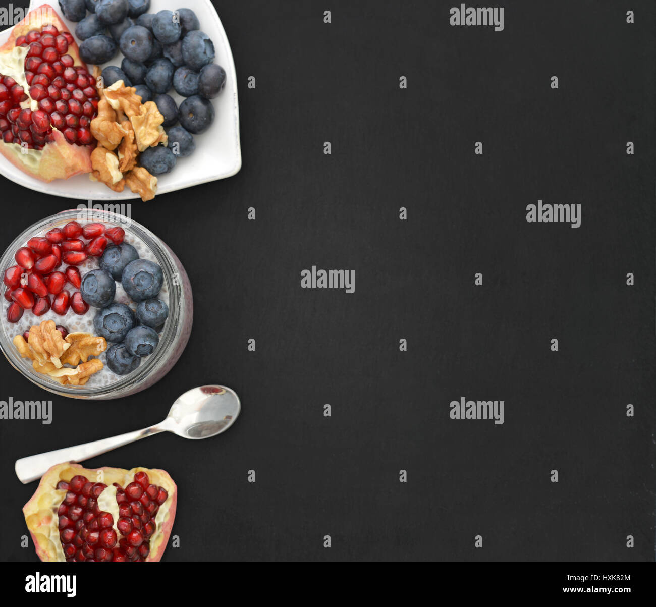 Pudding with chia seeds, yogurt and fresh fruits in glass jars on black background, top view Stock Photo