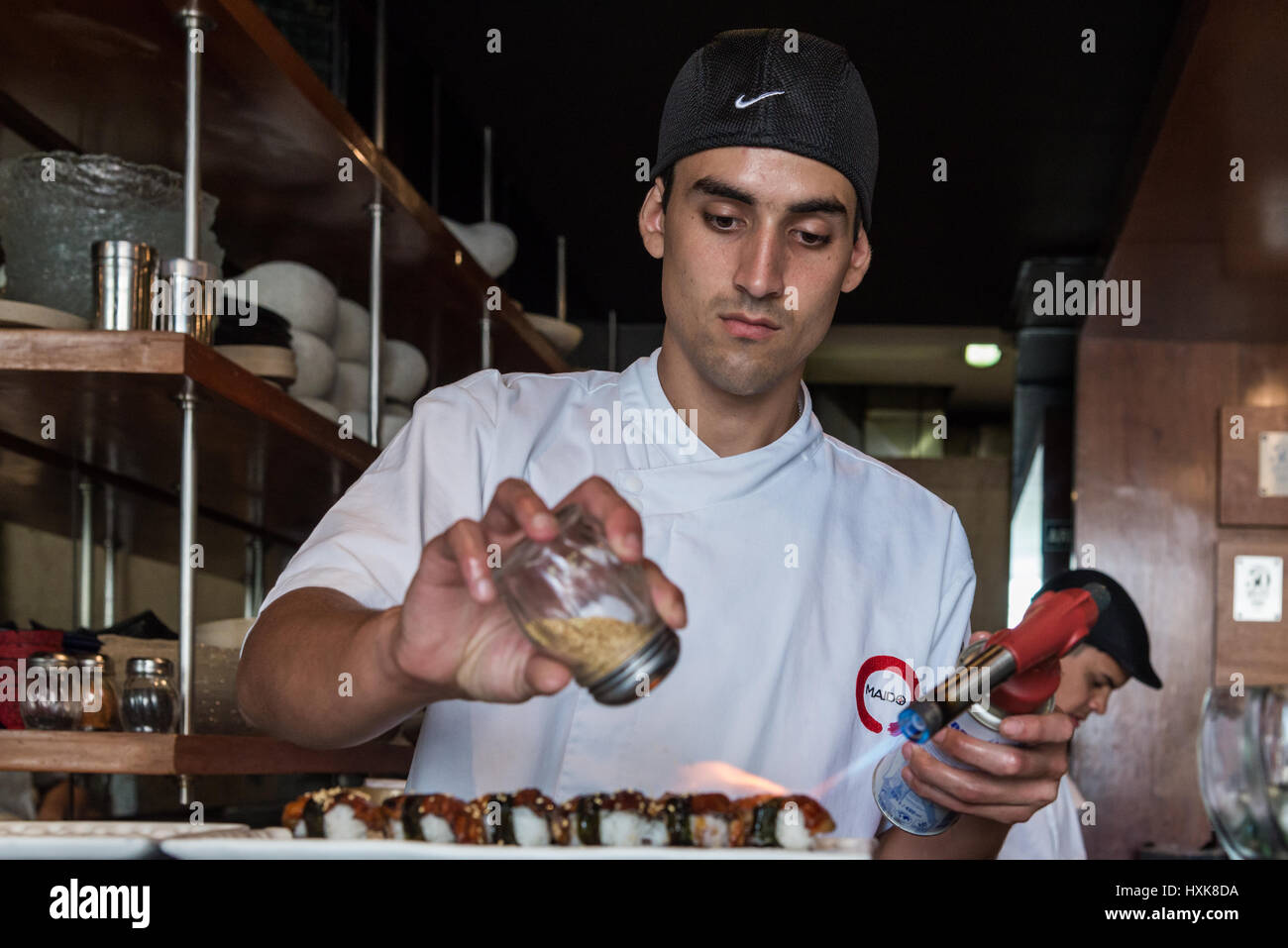A young Sushi chef cooking with a blow torch at the Maido Restaurant. Lima, Peru. Stock Photo