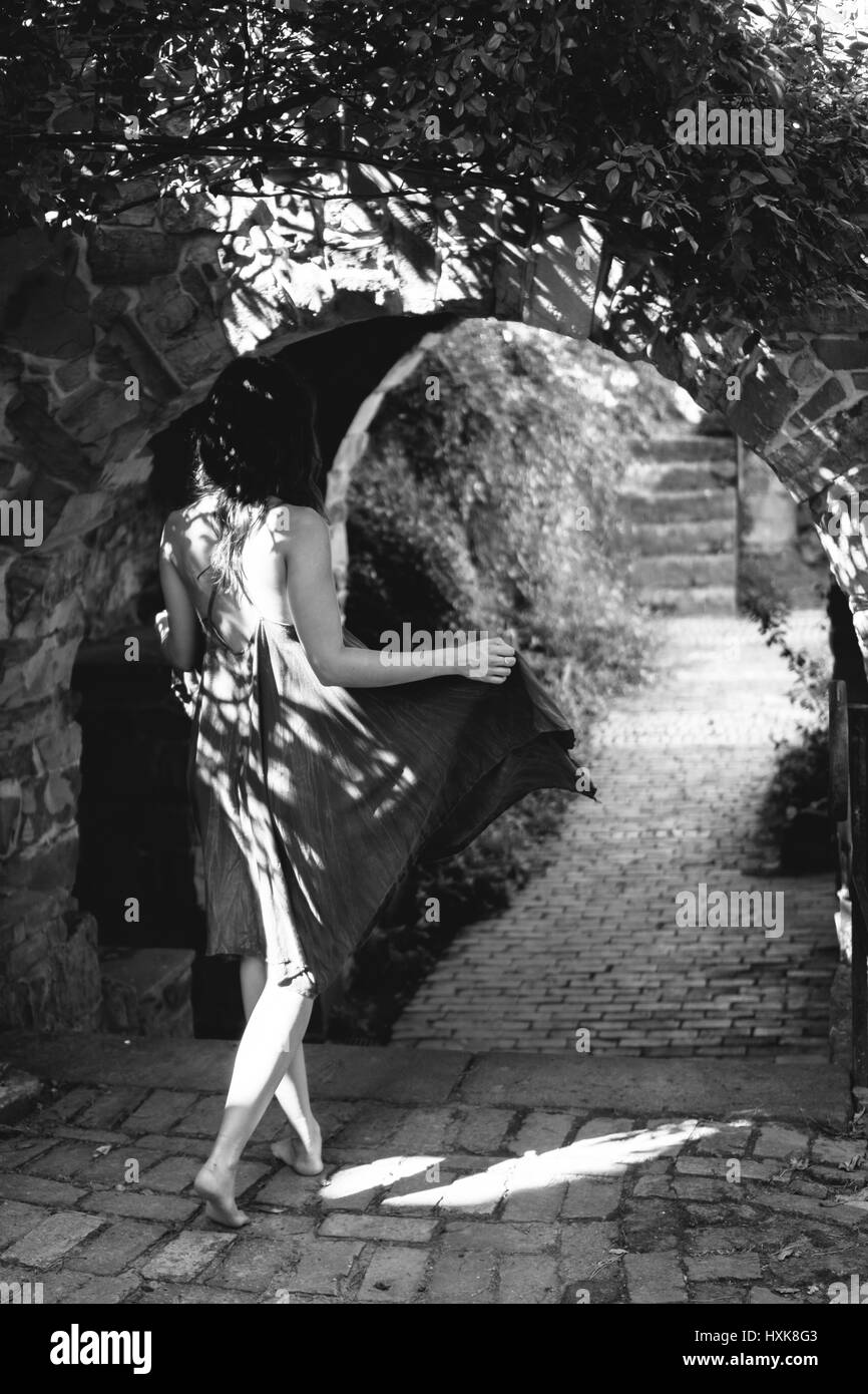 Girl walks through stone archway Stock Photo - Alamy