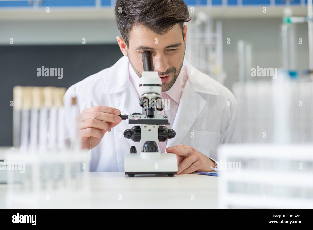 Man scientist in white coat working with microscope in lab Stock Photo ...