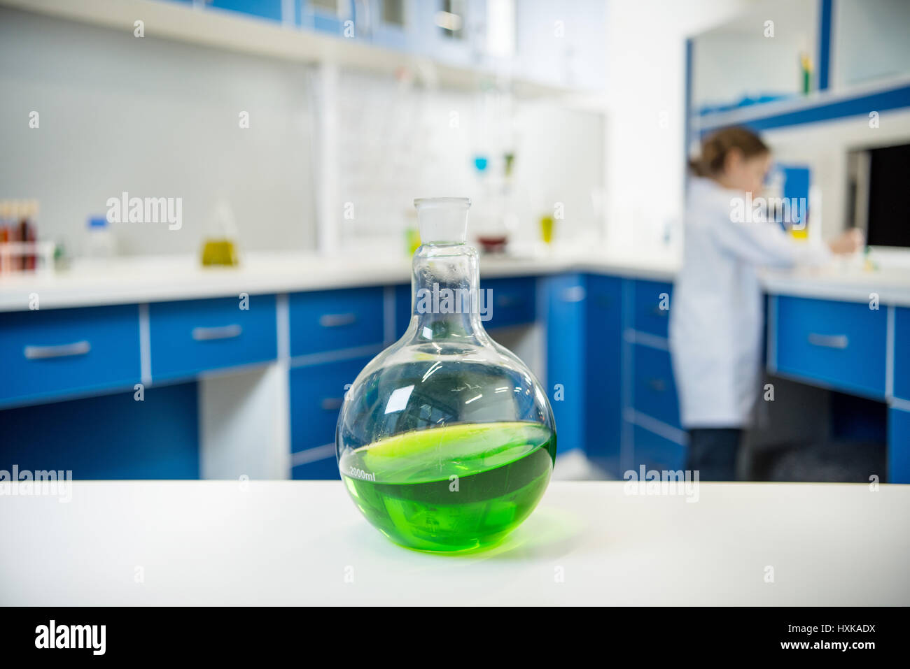 close up view of glass tube wit liquid on lab table with scientist