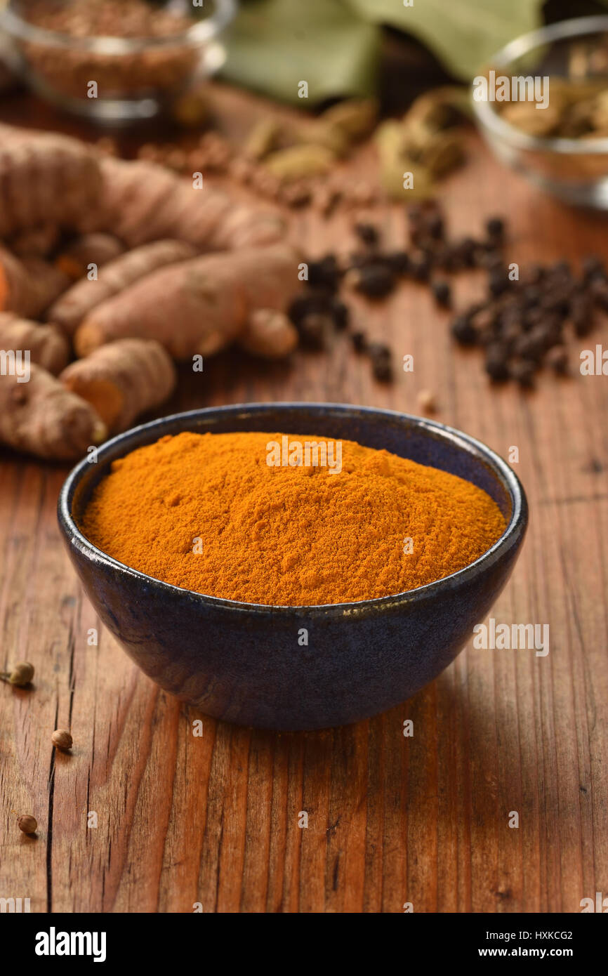 Ground turmeric powder in a bowl on wooden background. Healthy spice. Stock Photo