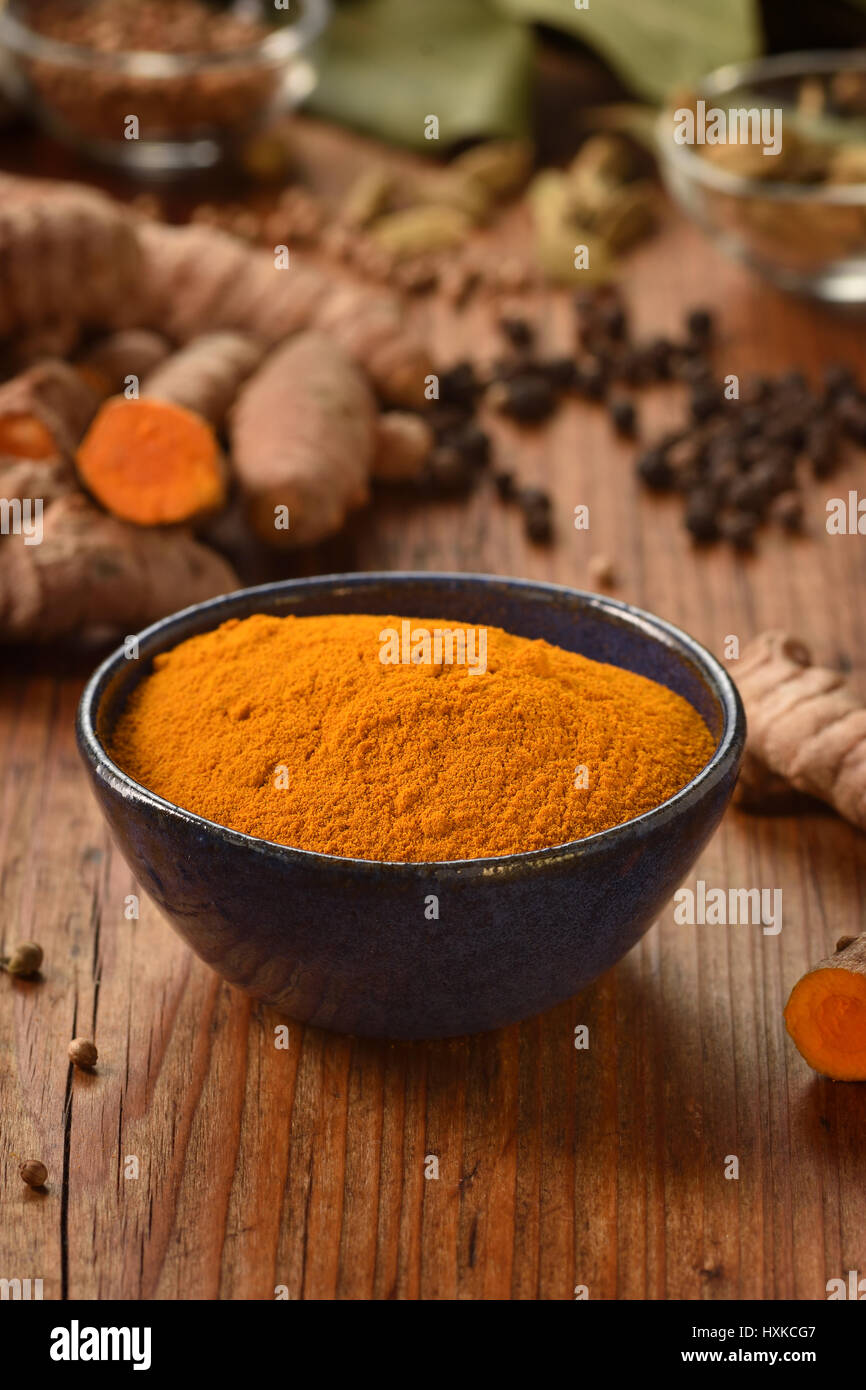 Ground turmeric powder in a bowl on wooden background. Healthy spice. Stock Photo