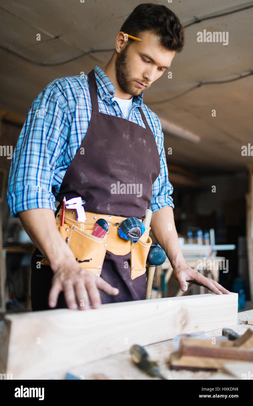 Examining plank of wood in workshop Stock Photo