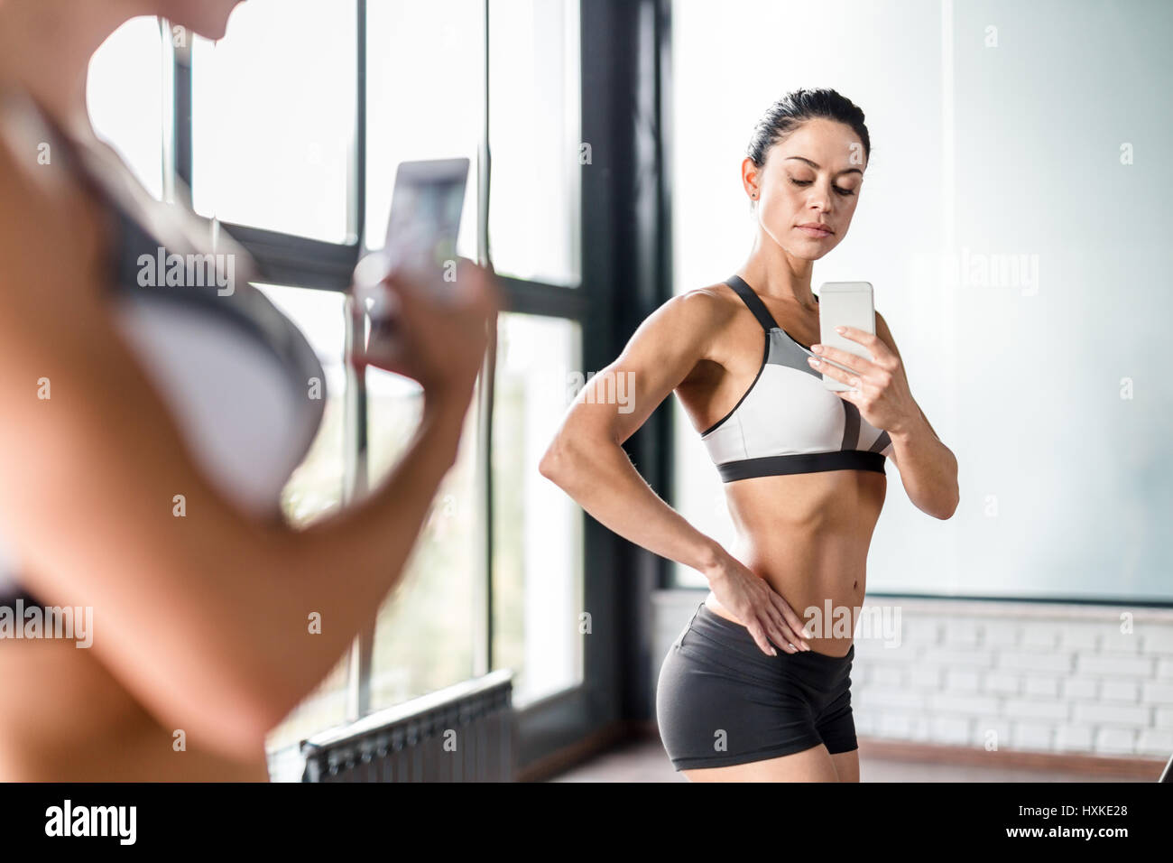 Sportive Woman Posing for Mirror Selfie Flexing Muscles Stock Photo