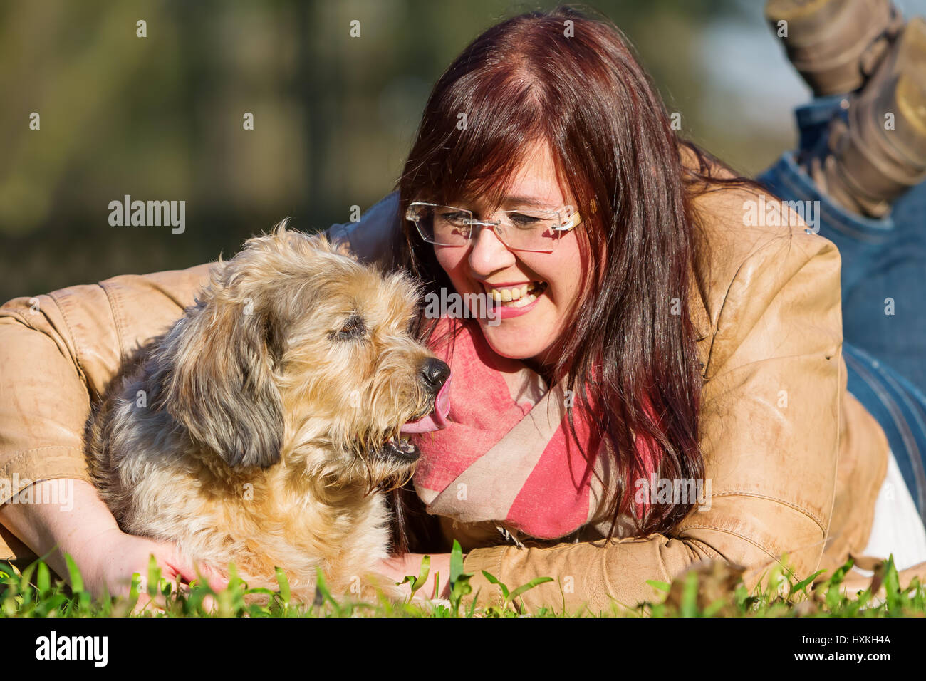 portrait of a young woman lying with her dog in the grass Stock Photo ...