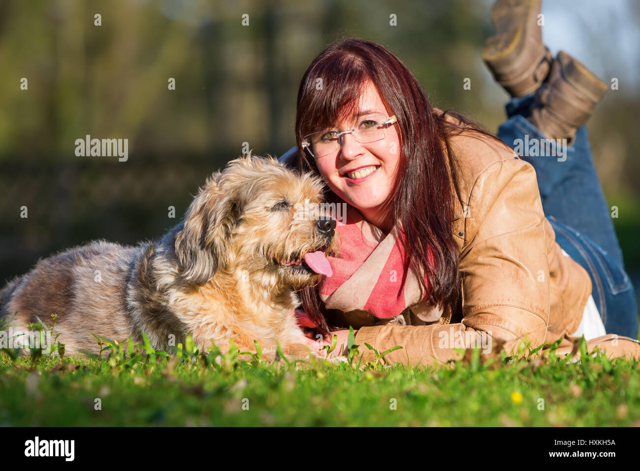 portrait of a young woman lying with her dog in the grass Stock Photo ...
