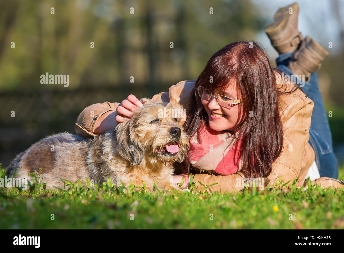portrait of a young woman lying with her dog in the grass Stock Photo ...