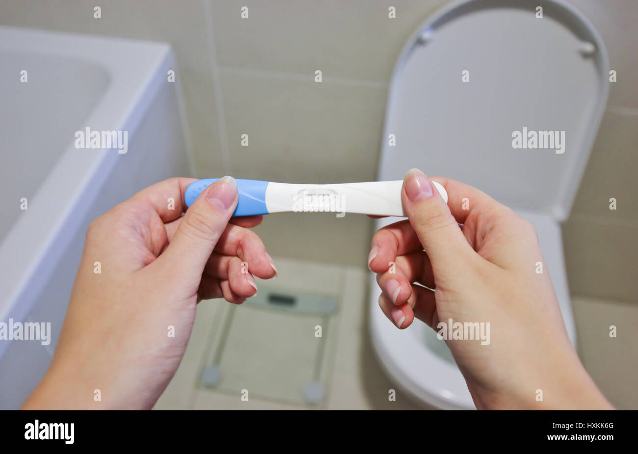 Woman Holding positiv Pregnancy Test in toilet Stock Photo