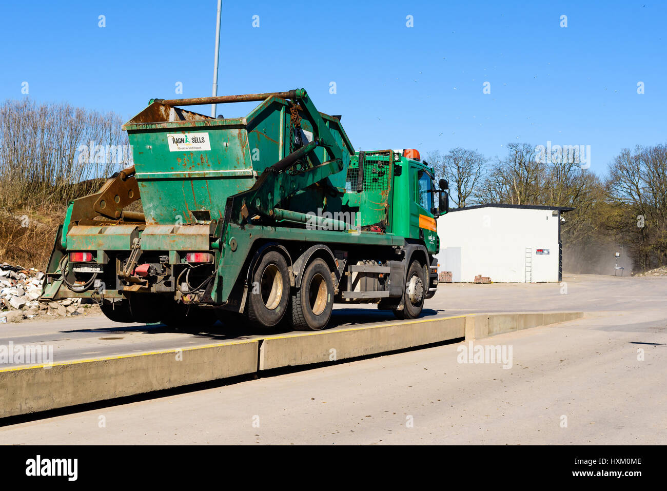 Ronneby, Sweden - March 27, 2017: Documentary of waste management. Green container truck Scania P420 being weighed on a truck scale before entering ga Stock Photo