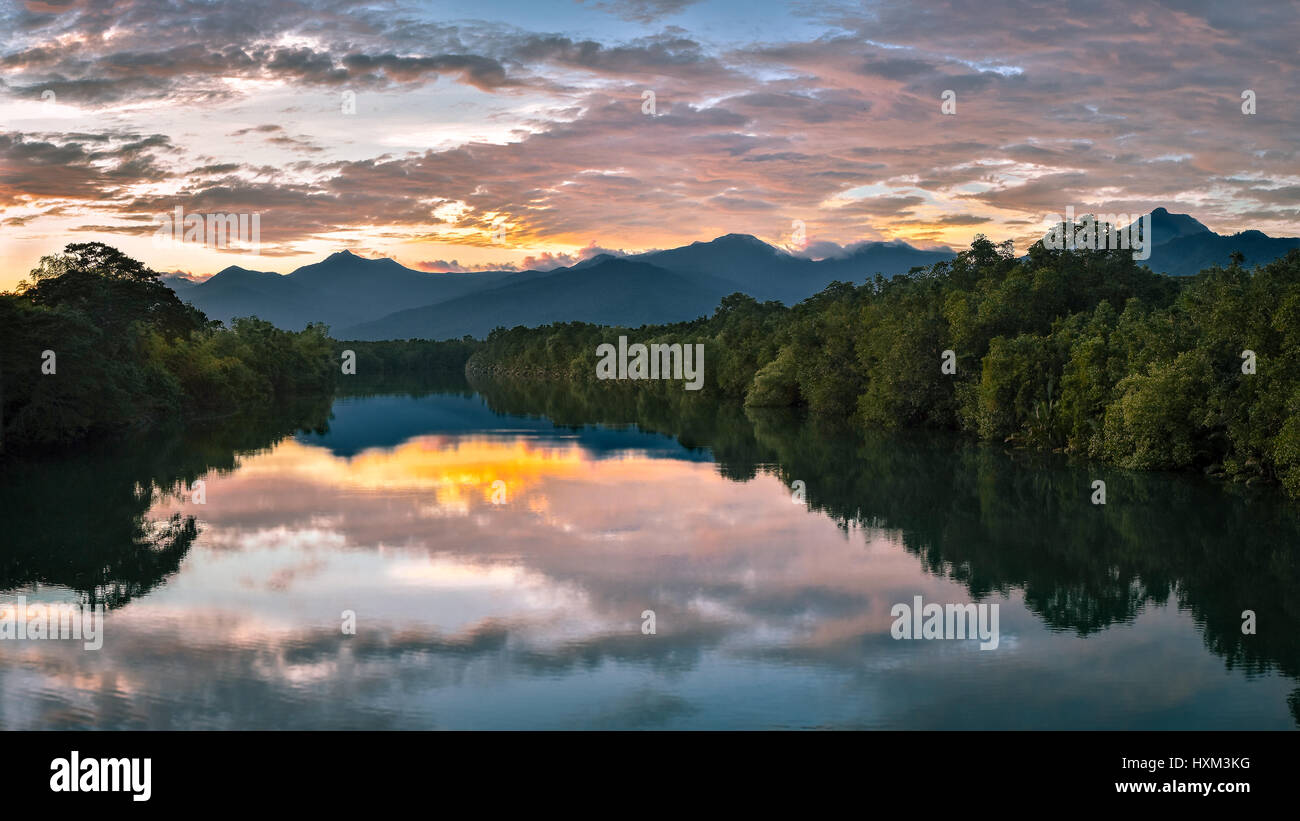 Sunset and clouds reflecting in a large wide still tree lined mirror like river, puerto princesa, Philippines. Stock Photo