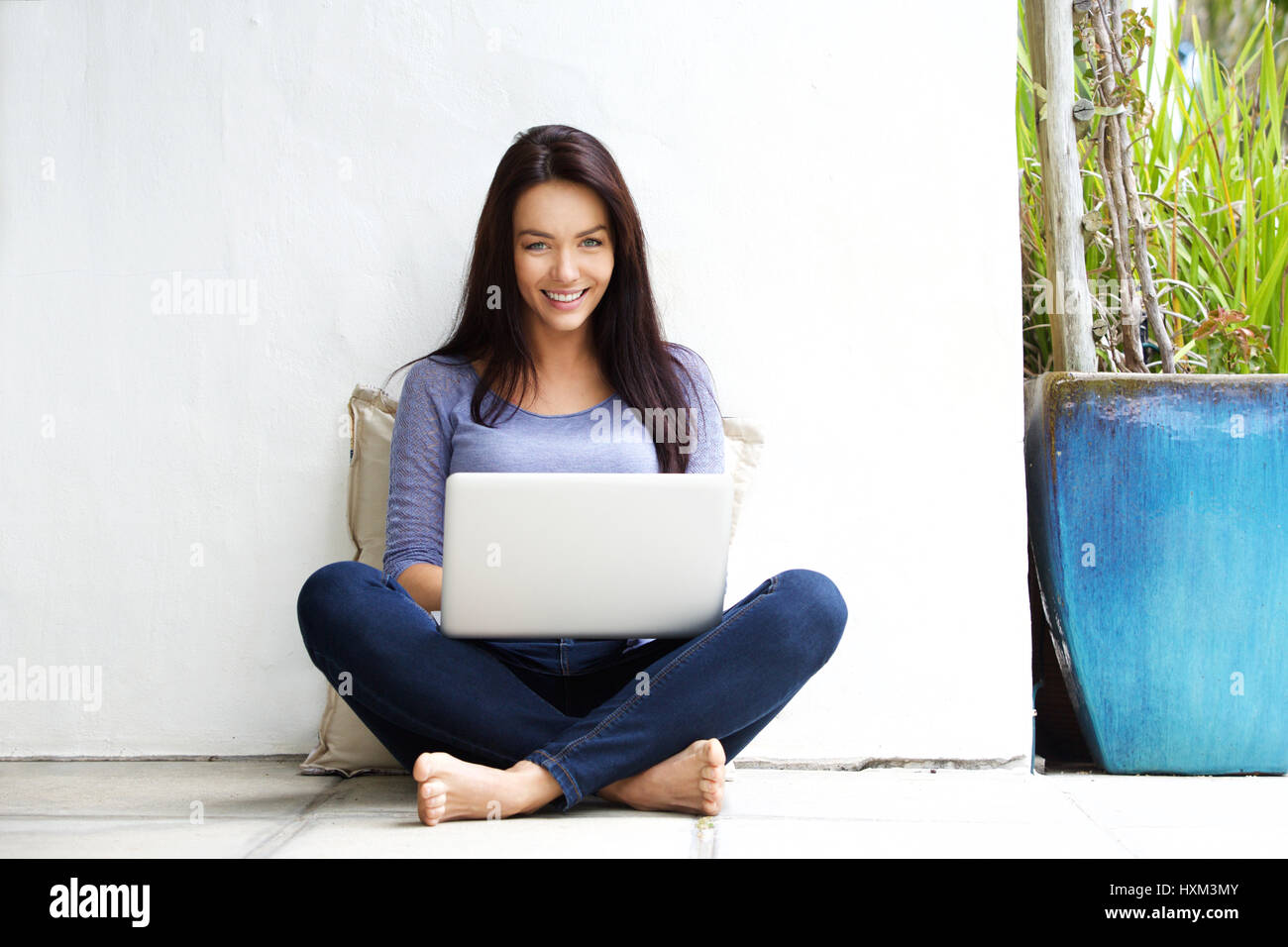 Portrait of happy young woman sitting on floor with a laptop Stock ...