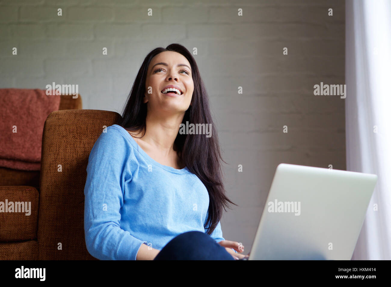 Portrait of a smiling young woman relaxing at home with a laptop Stock ...